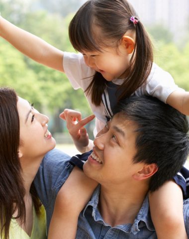 Chinese Family Giving Daughter Ride On Shoulders In Park